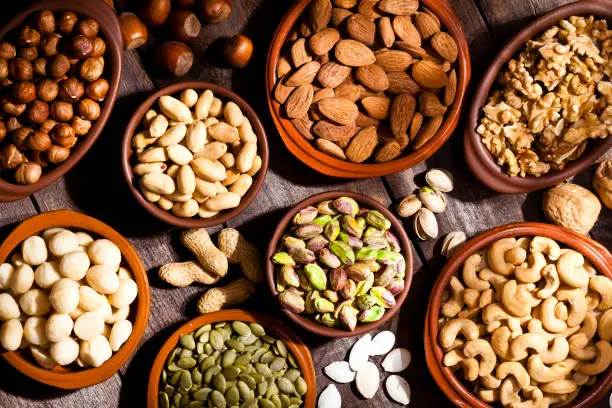 Assorted premium nuts in bowls, including almonds, cashews, walnuts, pistachios, and sunflower seeds, showcasing a variety of healthy snacks.